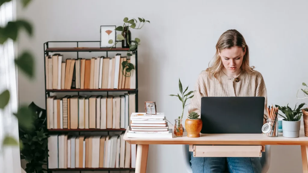 Une femme assis à son bureau devant son ordinateur portable, travaille dure à la tâche.