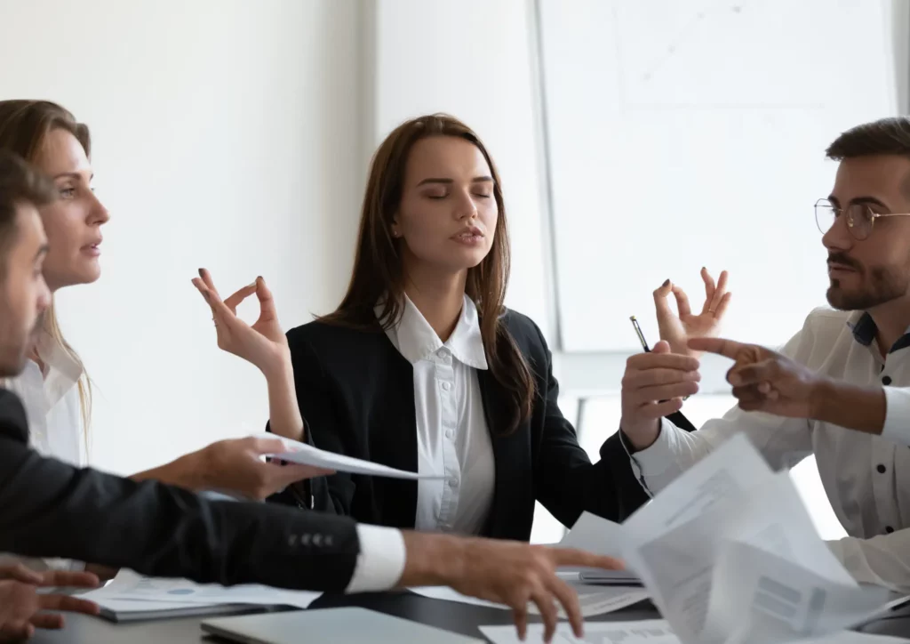 Une femme en réunion profite d'une méditation pendant que ses collègues débattent.
